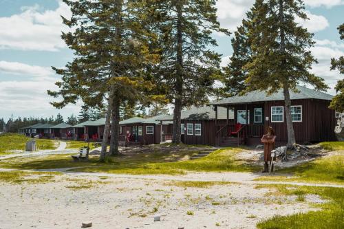 a woman standing in front of a cabin with trees at White Point Beach Resort in Summerville Centre