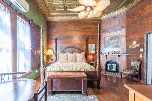 um quarto com uma cama, uma ventoinha de tecto e uma lareira em The Gallery House Boutique Hotel em Stephenville