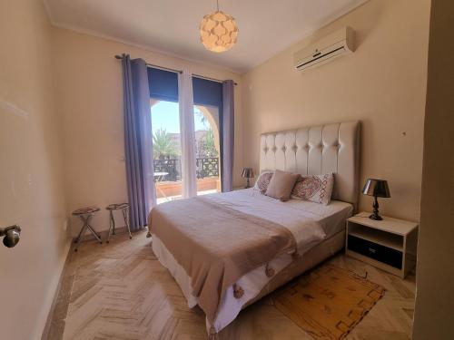 a bedroom with a large bed and a large window at La Perle de Marrakech by Atlas Golf Resort in Marrakech