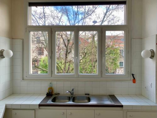 una cocina con 2 lavabos y 2 ventanas en Paris Apartment 5-minute walk to tube station, en Les Lilas