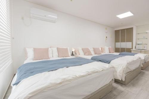 two large beds in a room with white walls at Mirae_stay 33 New Open [2 Queen+1 S-Single] in Seoul