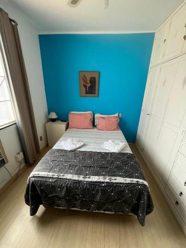 1 dormitorio con 1 cama grande y pared azul en Suíte Hotel São José en Caxambu