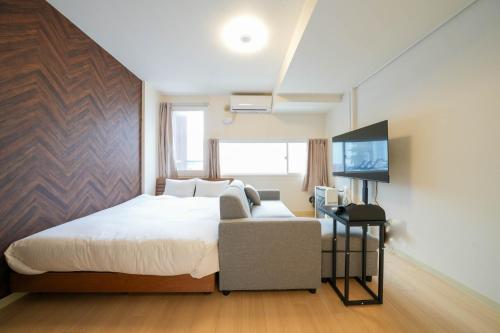 1 dormitorio con cama, sofá y TV en Liberte Nakajima Park Room 201,302 - Vacation STAY 98216v, en Sapporo