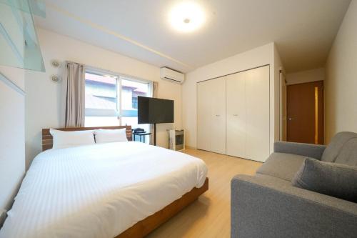 a bedroom with a large white bed and a couch at Liberte Nakajima Park Room 201,302 - Vacation STAY 98202v in Sapporo