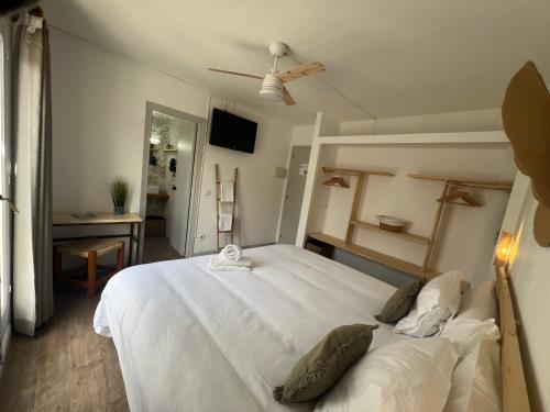 a bedroom with a large white bed with a ceiling fan at Balear Hotel in Ciutadella