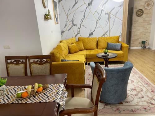 ein Wohnzimmer mit einem gelben Sofa und einem Tisch in der Unterkunft Yellow House Suite in Madschdal Schams