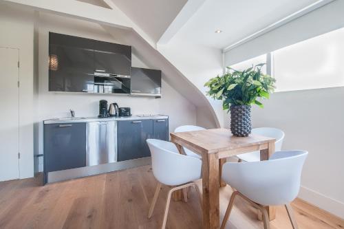 a kitchen with a wooden table and white chairs at Museumpark Apartments in Rotterdam