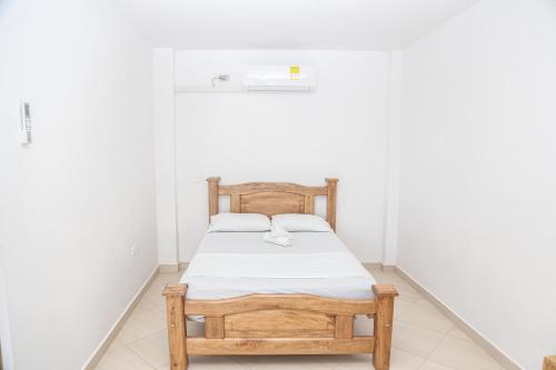 a bedroom with a wooden bed in a white room at Hotel Caribe Coveñas in Coveñas