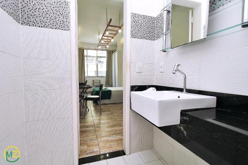 ein weißes Badezimmer mit einem Waschbecken und einem Spiegel in der Unterkunft Studio para 4 pessoas com vista mar em Copacabana in Rio de Janeiro