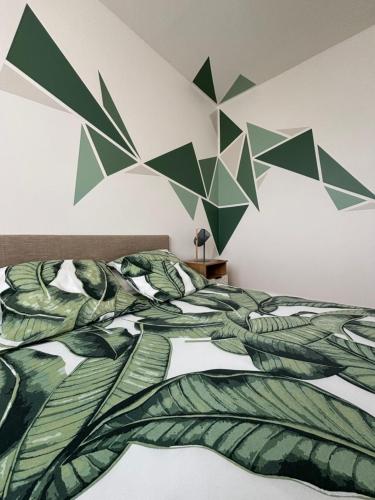 a bedroom with a bed with leaves on the wall at Casa Ragazzi - Refait à neuf - Calme - Parking in Lempdes