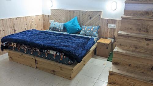 MOKSHA COTTAGES AND WOODHOUSE في كاسول: غرفة نوم مع سرير خشبي مع لحاف أزرق