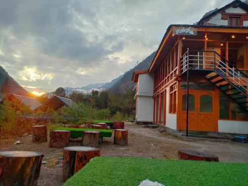 a building with a group of wooden stools in front of it at MOKSHA COTTAGES AND WOODHOUSE in Kasol