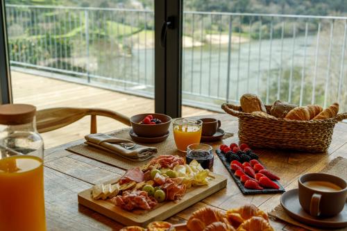 a table with breakfast foods and orange juice on it at Dajas Douro Valley - Exclusive Villas in Sande