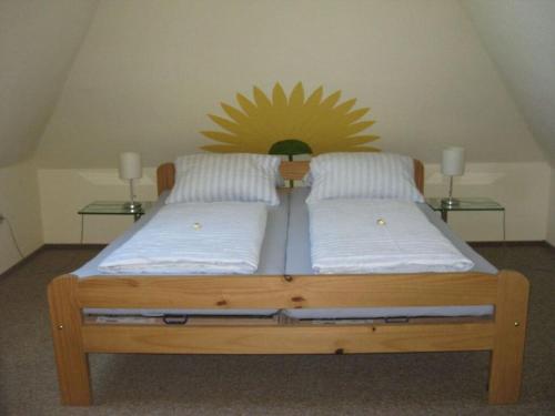 een houten bed met twee kussens en een zon aan de muur bij Holiday apartment for the Franck family in Heiligenhafen