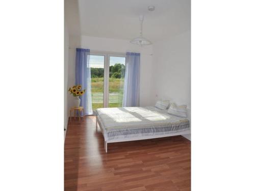 a white bedroom with a bed and a window at Holiday home Lutowsee 