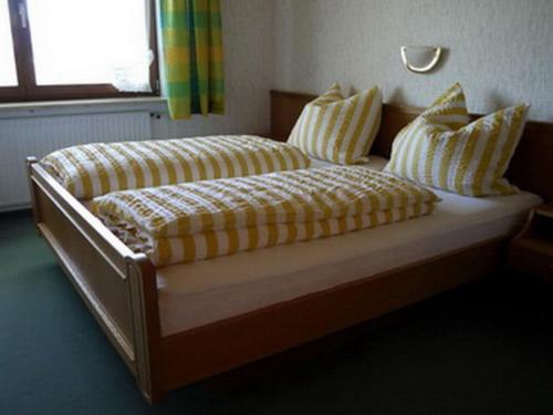a bed with yellow and white striped sheets and pillows at Holiday apartment Hildegard birds in Oberreute