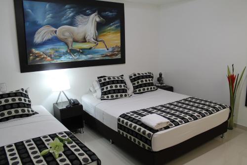 a bedroom with two beds and a painting of a horse at La Cabrera Hotel Boutique in Neiva