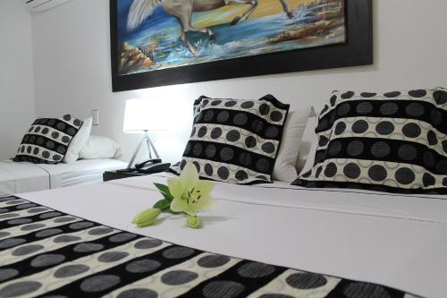 a bed with black and white pillows and a flower on it at La Cabrera Hotel Boutique in Neiva