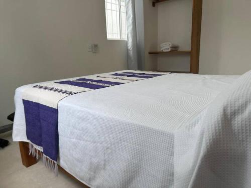 a bed with a blue and white blanket on it at Casa Maya en el mejor lugar de Puerto Escondido in Puerto Escondido