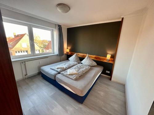 ein Schlafzimmer mit einem Bett und einem großen Fenster in der Unterkunft Haus Elbe Wohnung #15 - 10 min zu Fuß zum Strand in Cuxhaven