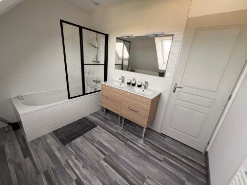 a bathroom with a sink and a tub and a mirror at Maison chaleureuse tout confort in Amboise