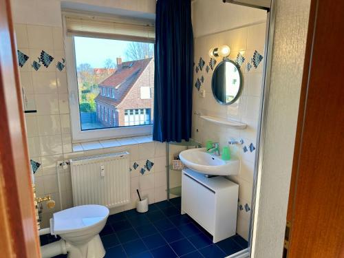 ein Badezimmer mit Waschbecken und Toilette und einem Fenster in der Unterkunft Haus Elbe Wohnung #15 - 10 min zu Fuß zum Strand in Cuxhaven