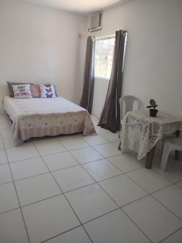 um quarto com uma cama, uma mesa e uma janela em Hostel da Prainha em Marechal Deodoro