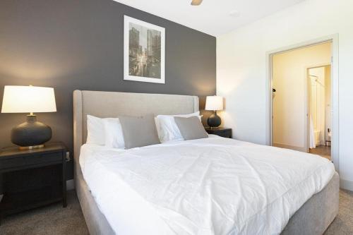 a bedroom with a large white bed and two lamps at Landing Modern Apartment with Amazing Amenities ID8348X93 in Kansas City