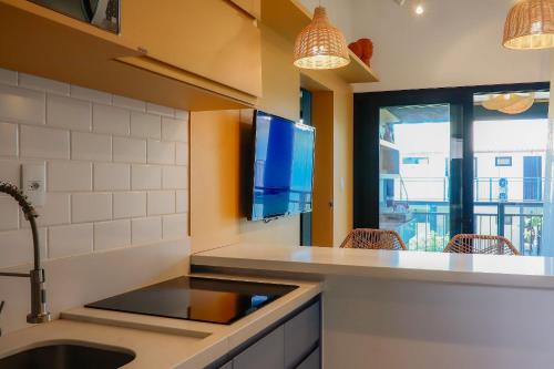 uma cozinha com um lavatório e uma televisão na parede em Lindo Quarto & Sala + SofaCama em Mata de São João