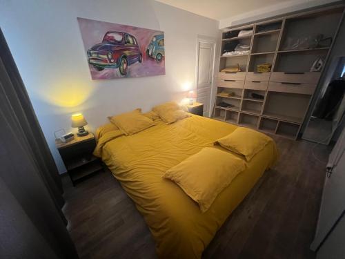 a bedroom with a yellow bed with a painting on the wall at Maison chaleureuse tout confort in Amboise