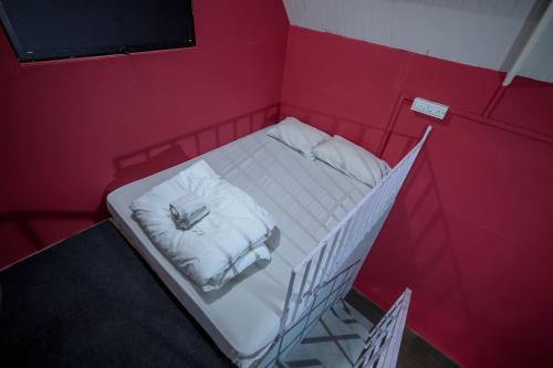 a small red room with a white bed in it at Konfudha Resort in Kalpetta