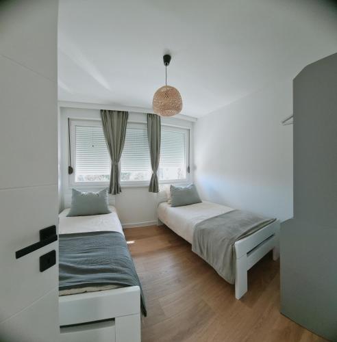 two beds in a room with two windows at Apartment Rea in Čapljina