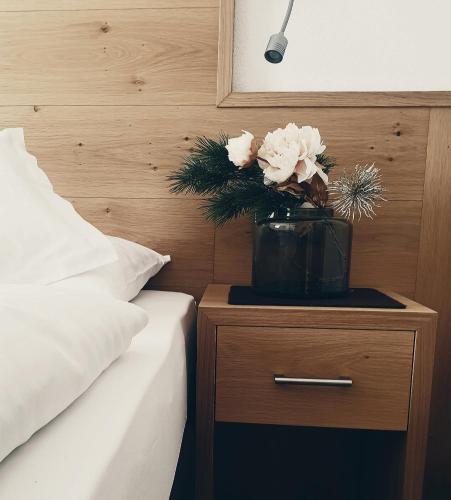 a vase of flowers on a night stand next to a bed at Garni Le Chalet in Santa Cristina in Val Gardena