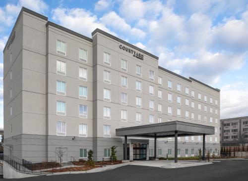 un grande edificio bianco con un baldacchino in un parcheggio di Courtyard by Marriott Seattle SeaTac Airport a Seattle