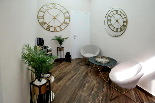 a living room with a clock and a table and chairs at Lustru Apartment in Catania