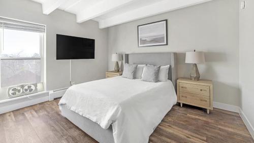 Landing - Modern Apartment with Amazing Amenities (ID3736X50) في دنفر: غرفة نوم بيضاء مع سرير وتلفزيون بشاشة مسطحة