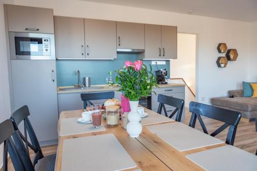 a kitchen and dining room with a wooden table with pink flowers at Lila akác vendégház in Keszü