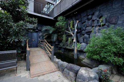 a house with a pond in front of a stone wall at Konfudha Resort in Kalpetta