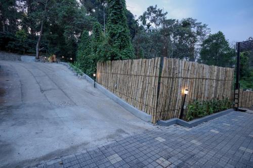 a fence on the side of a road next to a street at Konfudha Resort in Kalpetta