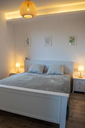 a bedroom with a large white bed with two lamps at Lila akác vendégház in Keszü
