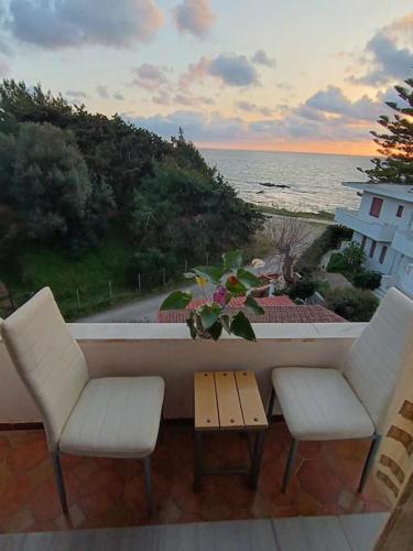 een balkon met 2 stoelen en een tafel en de oceaan bij Sunset View House in Preveza