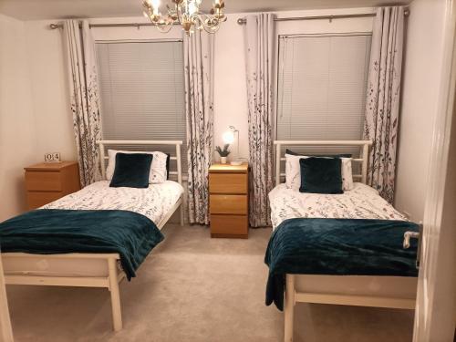 a bedroom with two beds and two windows at Mill cottage in Carrickfergus