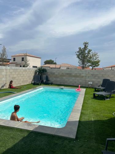 un homme qui se pose dans une piscine dans une cour dans l'établissement Appartement + piscine et extérieur, à Rivesaltes