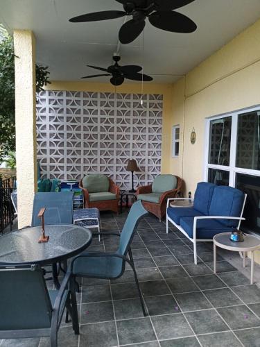 a patio with chairs and tables and a ceiling fan at Juliette - Studio, Sunset ocean views, pool. in Cruz Bay