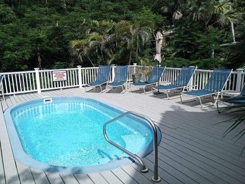 a hot tub on a deck with lounge chairs at Juliette - Studio, Sunset ocean views, pool. in Cruz Bay