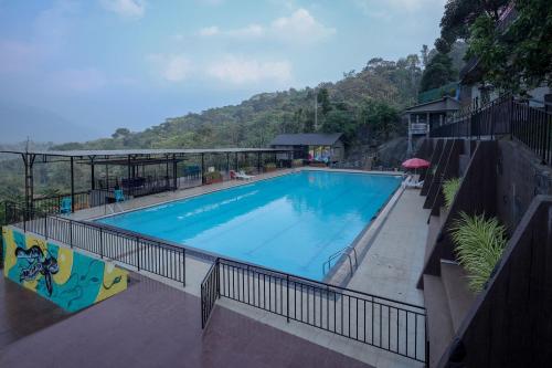 a large swimming pool with a mountain in the background at Konfudha Resort in Kalpetta