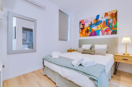 um quarto branco com uma cama e um espelho em Luminosa Holidays House em Olhão