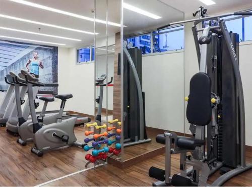 a gym with exercise equipment and a woman in the background at S4 HOTEL: Flat Lindo, Aconhegante e bem localizado in Brasilia
