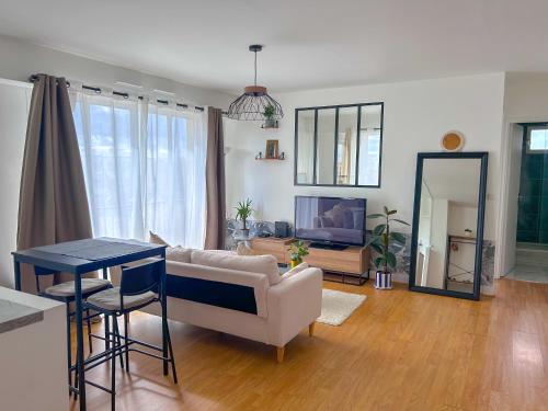 uma sala de estar com um sofá e uma mesa em Appartement lumineux rénové (proche JO) em Épinay-sur-Seine