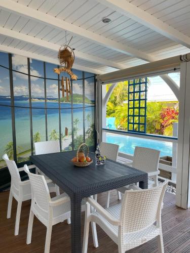 a dining room with a black table and white chairs at Résidence Subtropicale in Saint-François